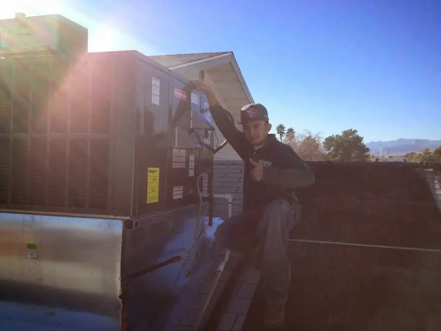 HVAC technician performing HVAC Inspection on a rooftop unit in Hope